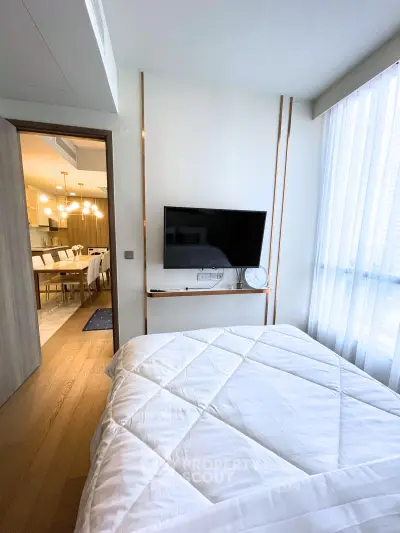 Modern bedroom with TV and view into stylish dining area