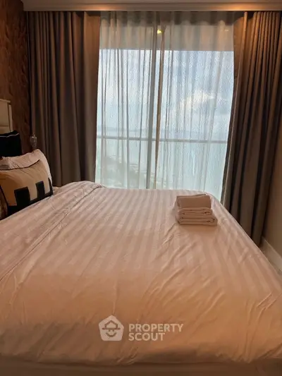 Cozy bedroom with large window and elegant bedding in modern apartment.