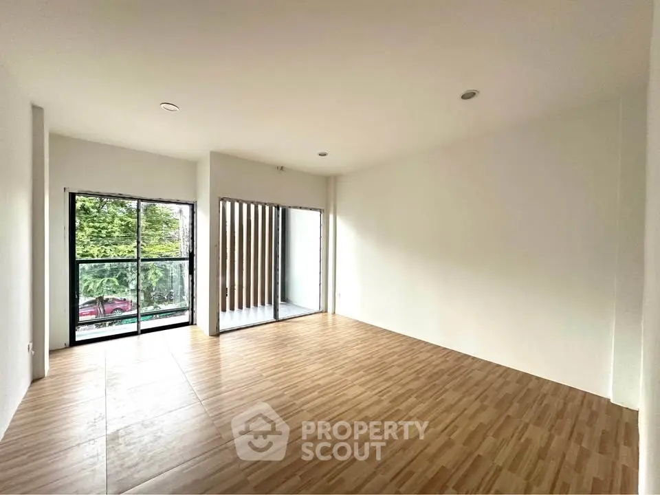 Spacious empty living room with large windows and wooden flooring, ideal for customization.
