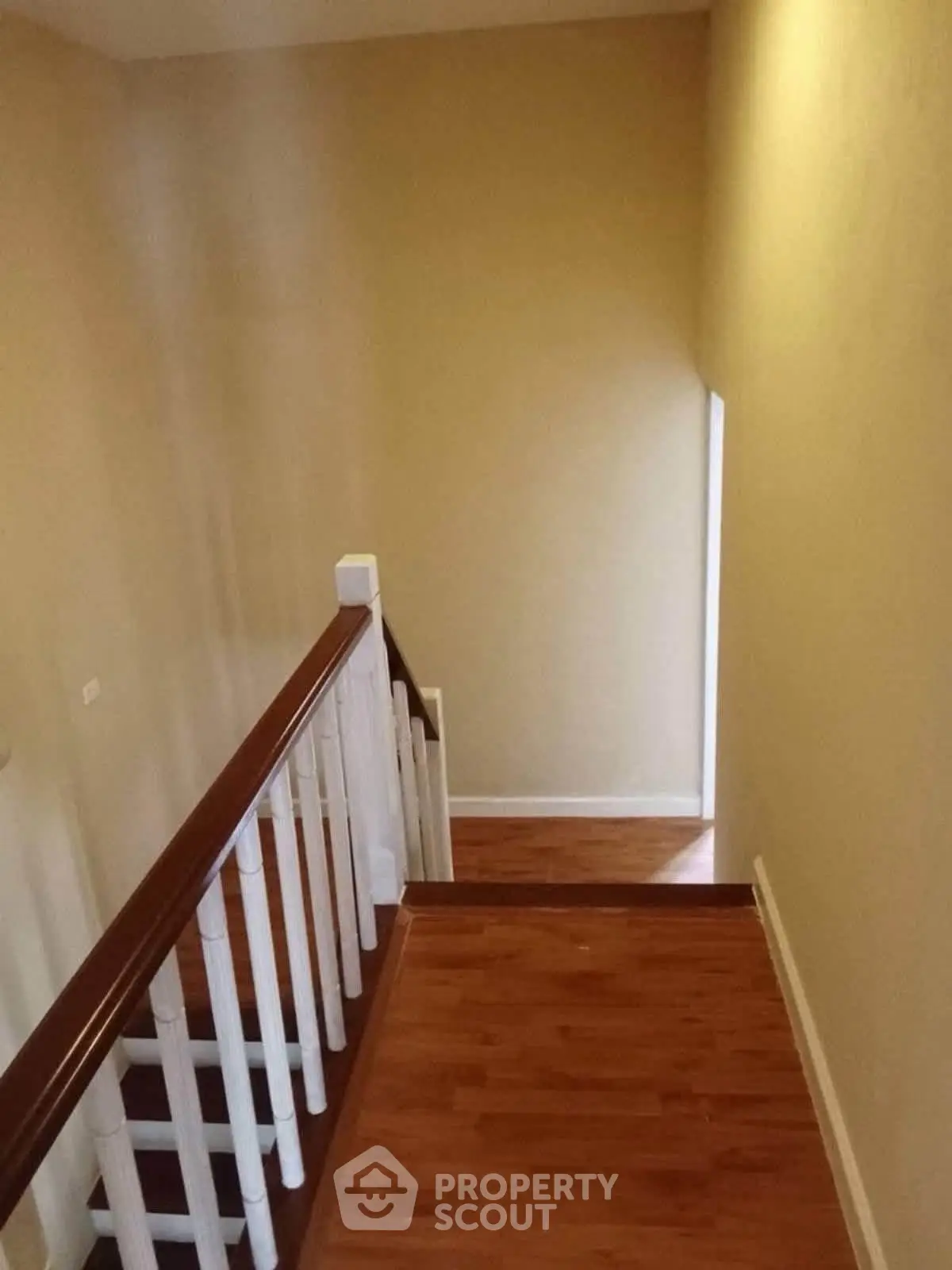 Elegant staircase with wooden flooring and white railing in a modern home interior.