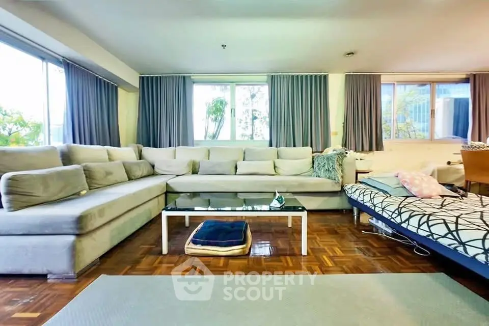 Spacious living room with modern L-shaped sofa and large windows offering natural light.