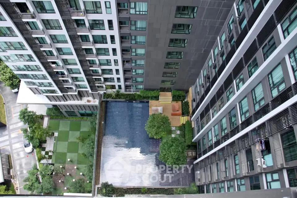 Stunning aerial view of modern apartment complex with pool and landscaped garden.