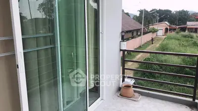 Charming balcony with sliding glass doors and scenic view of lush greenery.