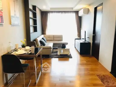 Modern living room with wooden flooring, stylish furniture, and natural light from large windows.