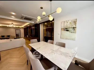 Luxurious open-plan living and dining area with elegant marble table and modern lighting fixtures.