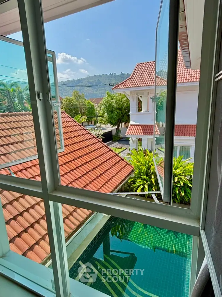 Charming villa with red-tiled roofs and pool view, surrounded by lush greenery and scenic hills.