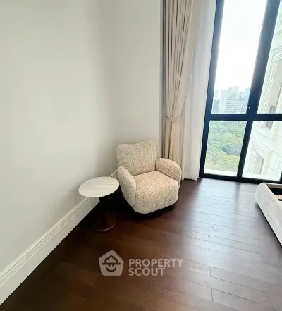 Elegant corner unit with cozy armchair and stunning city view from large window.