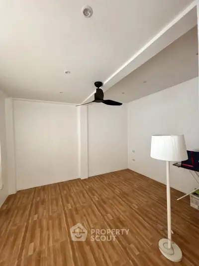 Spacious empty room with wooden flooring and ceiling fan, ideal for customization.