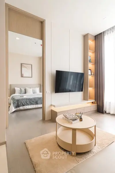 Modern living room with sleek TV setup and view into cozy bedroom
