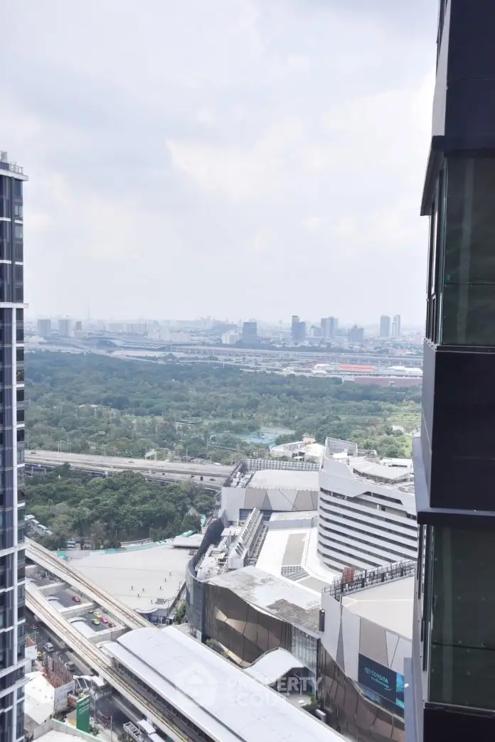 Stunning cityscape view from a high-rise building with lush greenery and urban skyline.