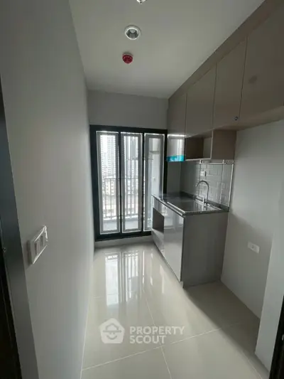 Modern compact kitchen with sleek cabinetry and balcony view