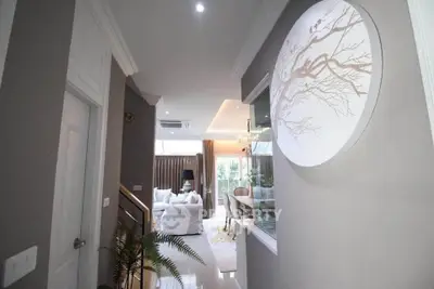 Elegant hallway leading to a bright living room with modern decor and large windows.