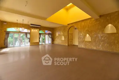 Spacious and elegant living room with large windows and golden walls, perfect for luxury living.