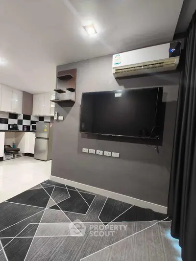 Modern living room with wall-mounted TV and sleek kitchen area