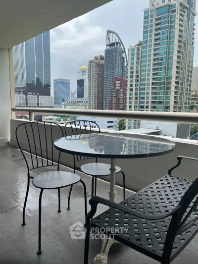 Stunning city view from a modern balcony with stylish outdoor seating, perfect for relaxation.
