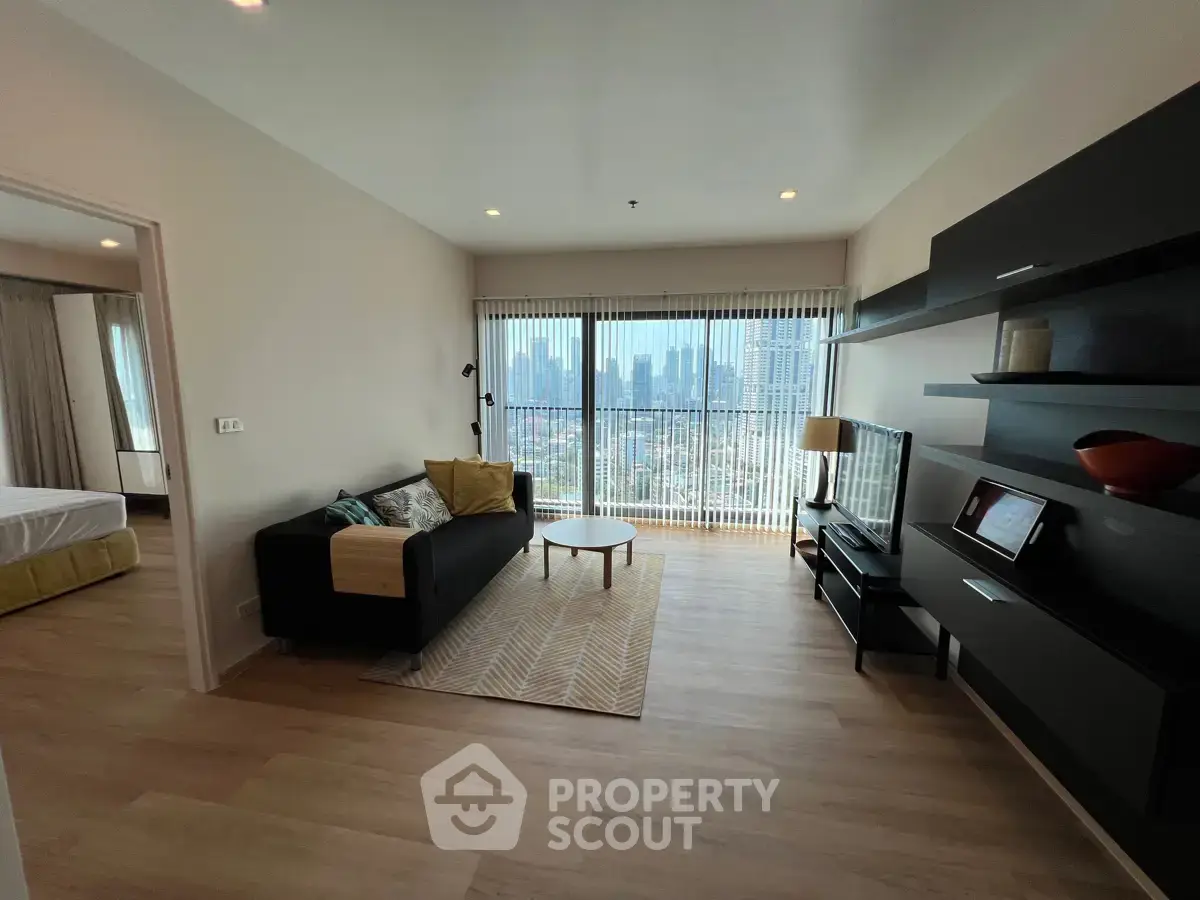 Modern living room with city view, stylish furniture, and natural light in a high-rise apartment.