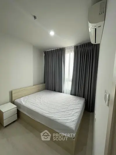 Modern bedroom with minimalist design, featuring a comfortable bed and sleek air conditioning unit.