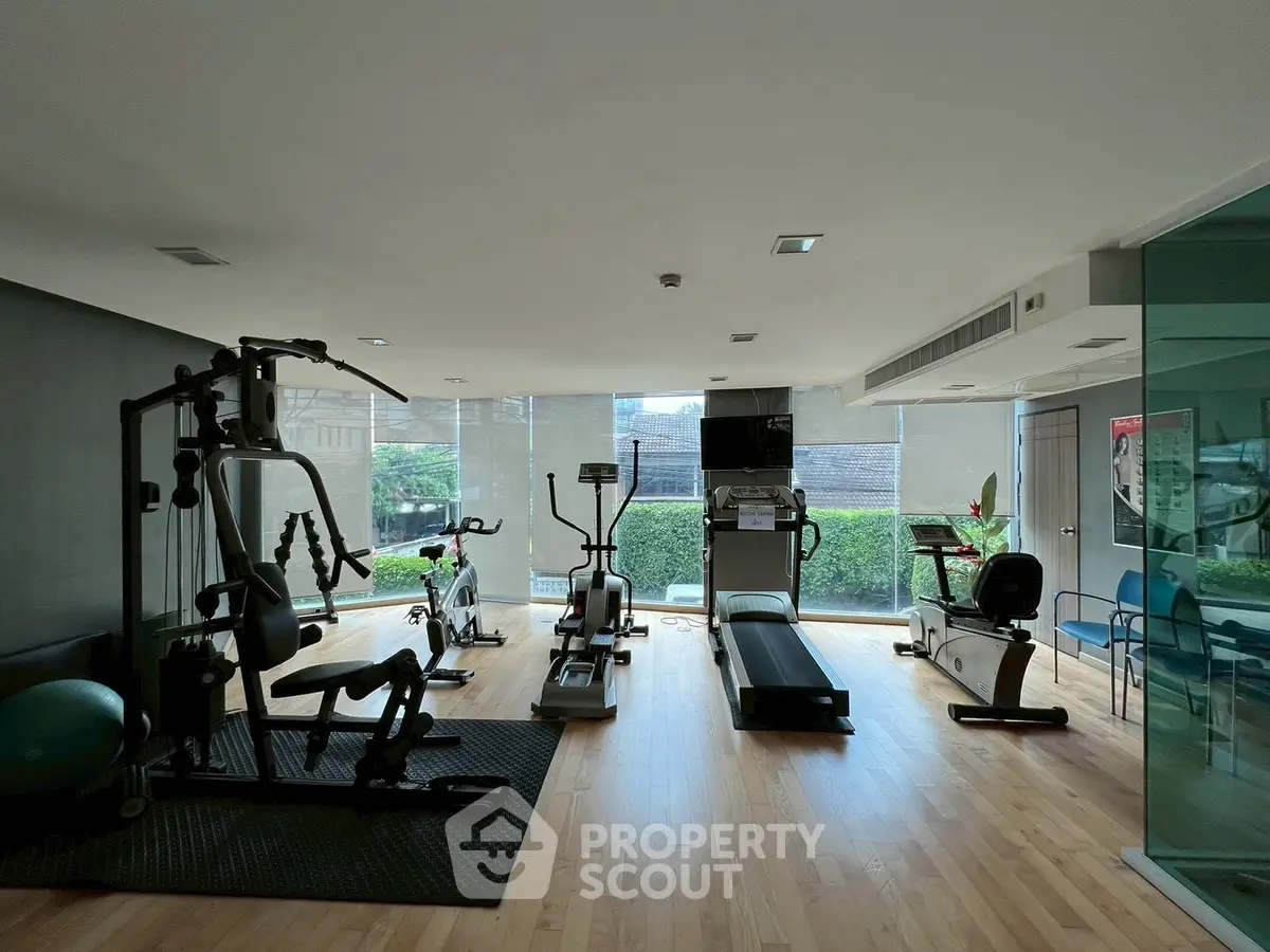 Modern gym with state-of-the-art equipment and large windows in a real estate property.