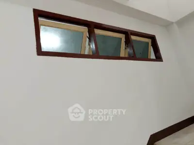 Minimalist interior wall with small high windows and wooden frames