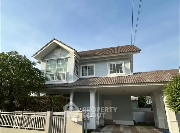 Charming two-story house with a spacious driveway and lush greenery, perfect for family living.