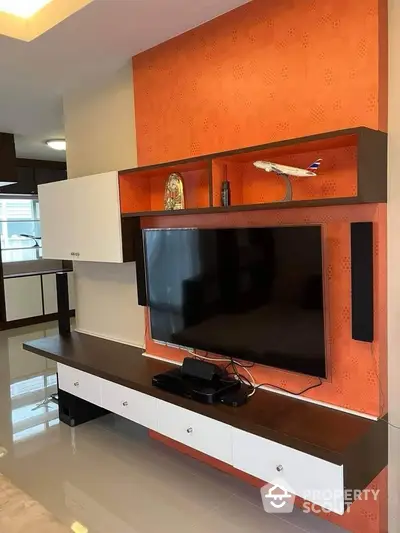 Modern living room with stylish TV unit and vibrant orange accent wall