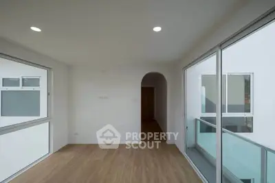 Modern minimalist room with large windows and wooden flooring, perfect for natural light lovers.