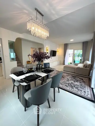 Elegant living and dining area with modern chandelier and stylish decor.