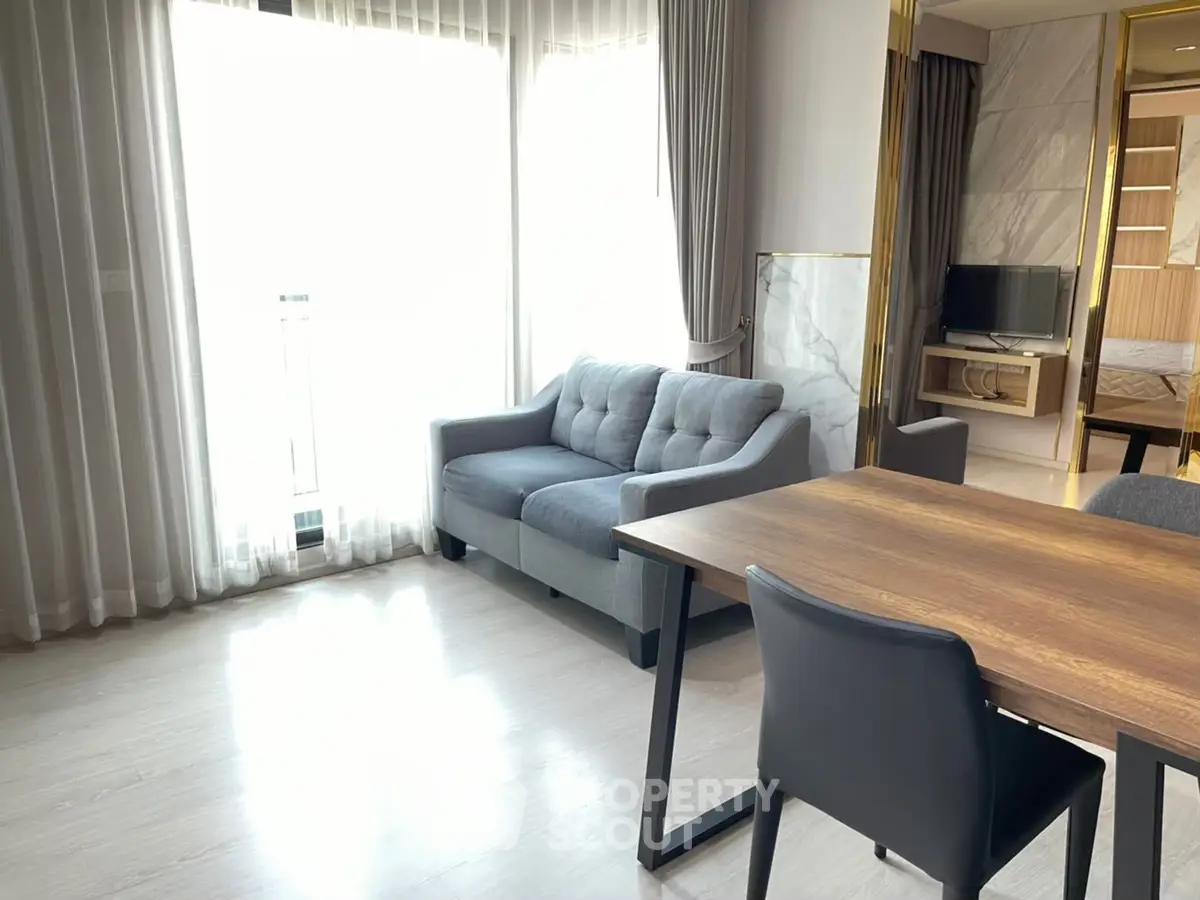 Modern living room with natural light, cozy sofa, and stylish dining area in a contemporary apartment.