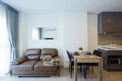 Modern living room with leather sofa and dining area in open-plan apartment.