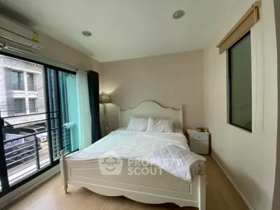 Cozy bedroom with elegant white bed and large window offering natural light and city view.