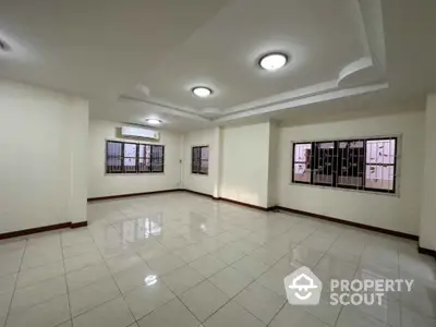 Spacious tiled living room with modern ceiling lights and large windows in a contemporary home.