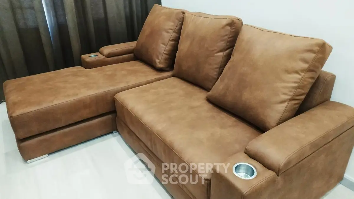 Luxurious brown leather sectional sofa with cup holders in modern living room setting.