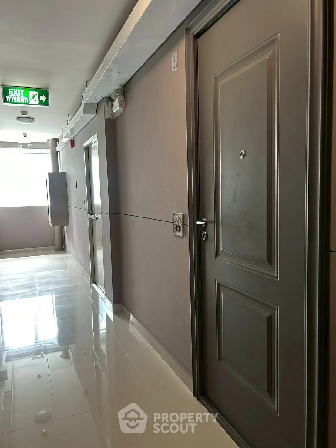 Modern apartment hallway with shiny floors and exit sign