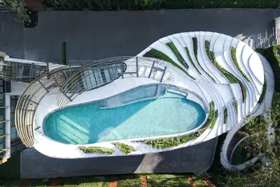 Stunning aerial view of modern architectural pool design with lush landscaping.