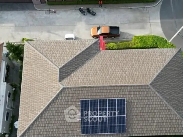 Aerial view of a house with solar panels on the roof in a suburban neighborhood.