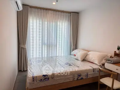 Cozy bedroom with large window and modern furnishings in a stylish apartment.
