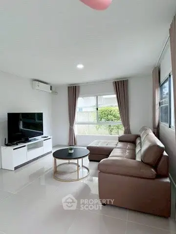 Modern living room with sleek leather sofa and large TV, bright natural light.