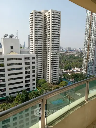Stunning high-rise balcony view with cityscape and lush greenery, perfect for urban living.