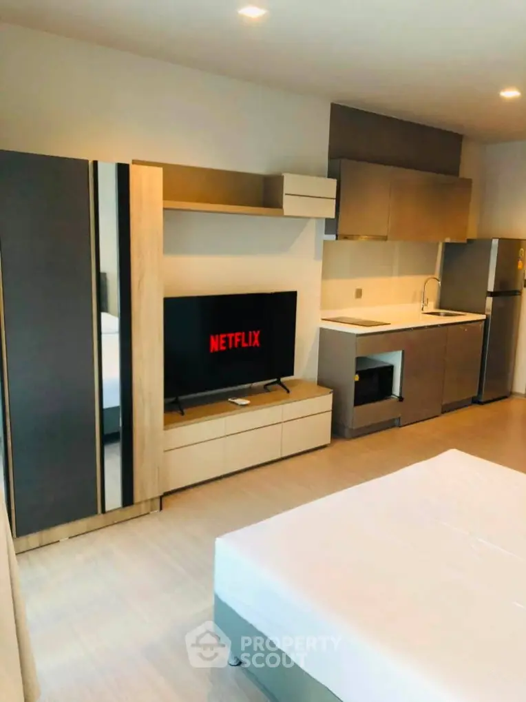 Modern studio apartment with sleek kitchen and entertainment area, perfect for urban living.