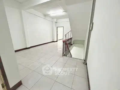 Spacious common area with tiled flooring and staircase in modern building