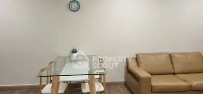 Modern living room with glass dining table and beige sofa, minimalist decor.
