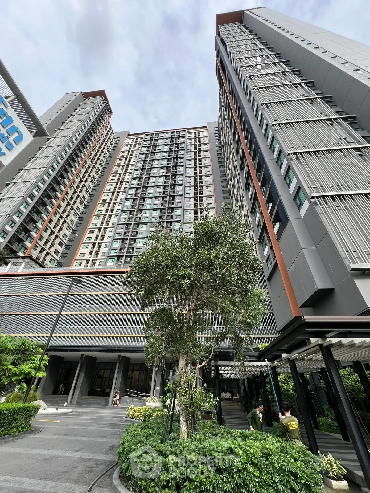 Modern high-rise residential building with lush landscaping and contemporary design.