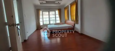 Spacious bedroom with wooden flooring and large windows for natural light.