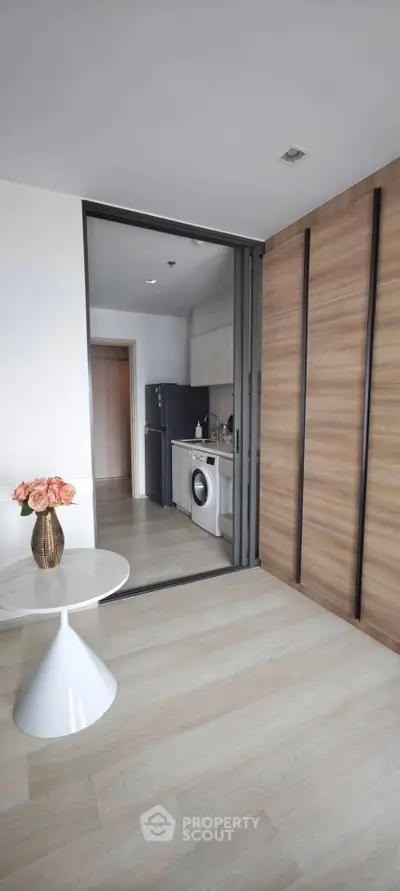 Modern apartment with open kitchen layout and sleek wooden sliding doors, featuring a washing machine and stylish decor.