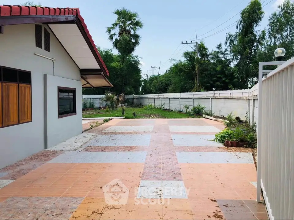 Spacious outdoor patio with tiled flooring and lush greenery, perfect for relaxation and gatherings.