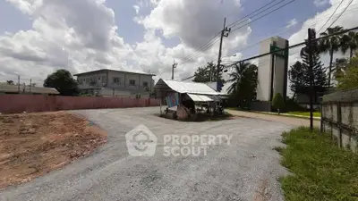 Vacant land with potential for development in a suburban area, featuring a small structure and nearby buildings.
