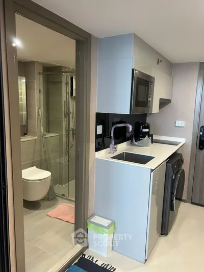 Compact modern kitchen with integrated appliances and adjacent bathroom