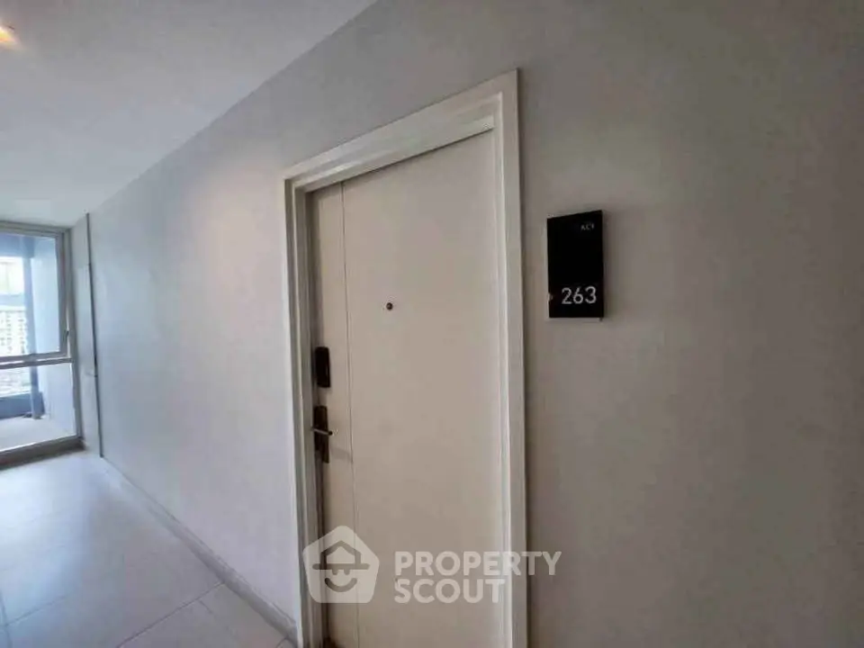 Modern apartment entrance with sleek door and room number 263, bright hallway with city view.