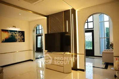 Luxurious living room with modern decor and large TV, featuring elegant arches and stylish lighting.