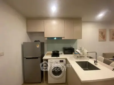 Modern kitchen with washing machine, fridge, and sleek cabinetry in a cozy apartment setting.